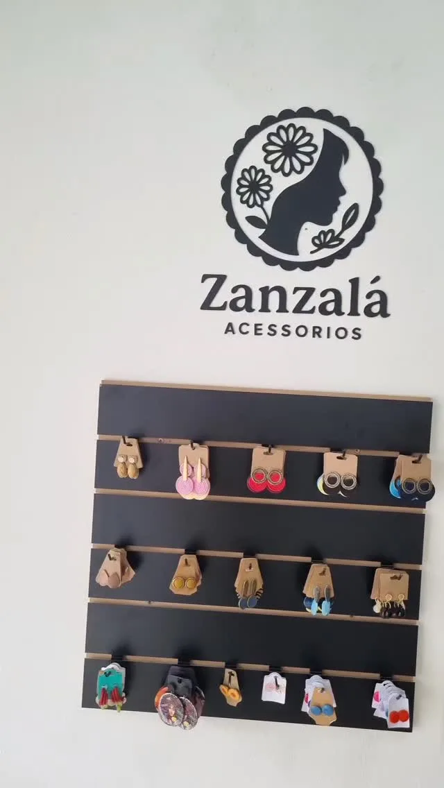 Painel de brincos na parede da loja Zanzalá Acessórios, sob o logo